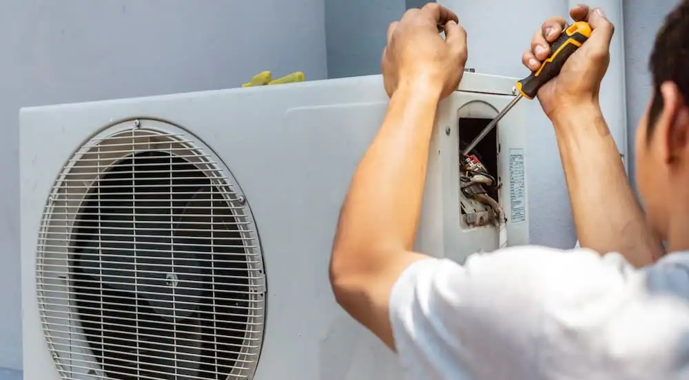 HVAC technician servicing the electrical panel of an outdoor heat pump