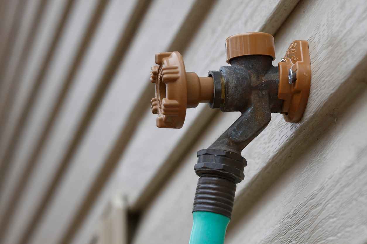 outdoor faucet connected to the siding of a house