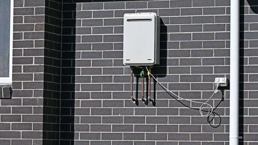 Tankless water heater mounted on a grey brick wall